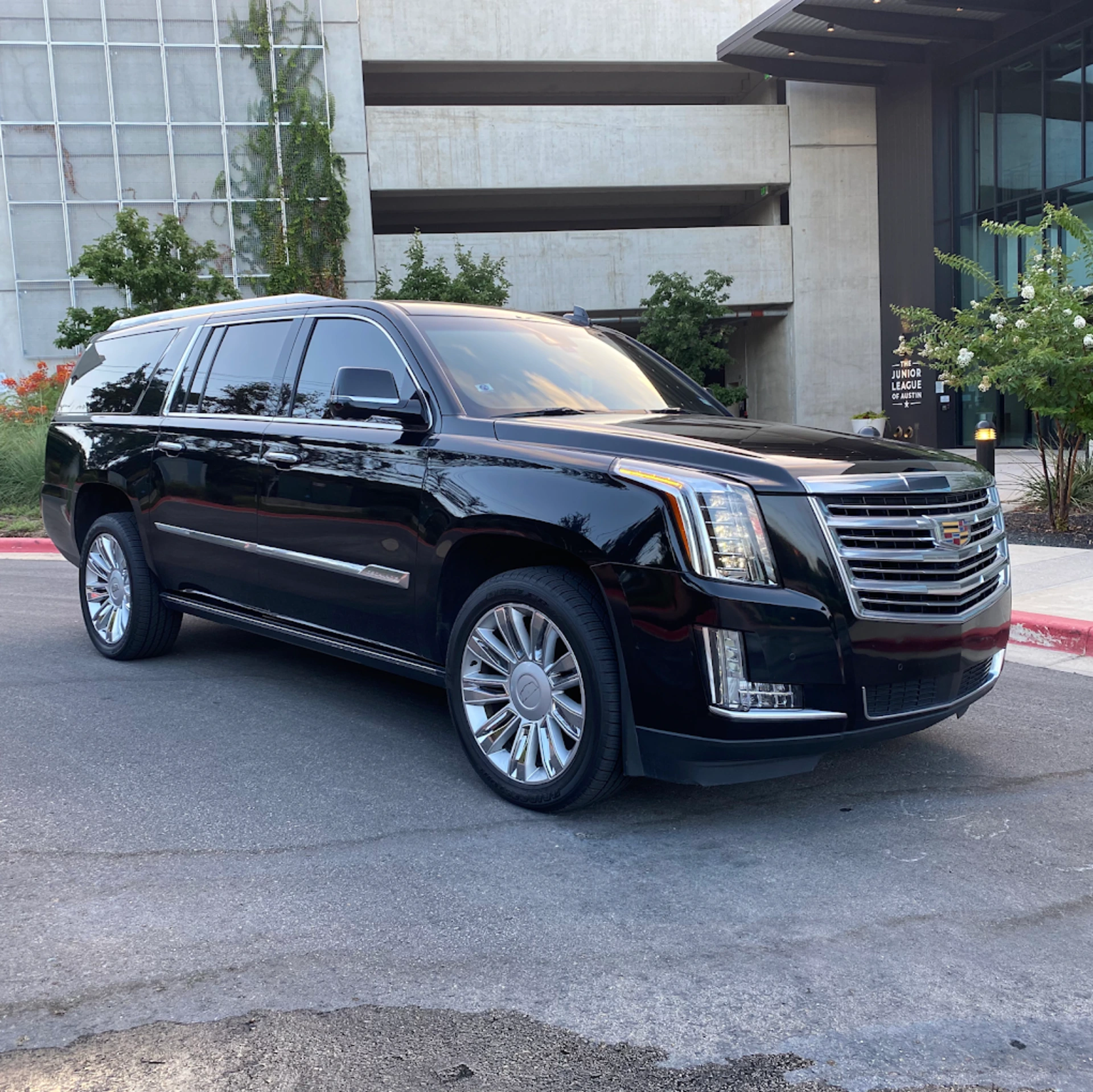 Cadillac Escalade luxury SUV providing executive transportation service in front of Fortune 500 corporate headquarters